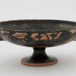 Attic black-figure kylix with Dionysiac procession on sides and satyr in tondo c. 500 BCE Ceramic 8.0cm (H) x 25.0cm (W) x 18.5cm (D) The University of Melbourne Art Collection. Gift of David and Marion Adams, 2009. 2009.0233.000.000 © Reproduction enquiries should be forwarded to the Ian Potter Museum of Art